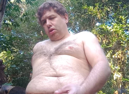 Boy in the woods sitting on a tree trunk pees and then jerks off with saliva coming from his mouth at the end
